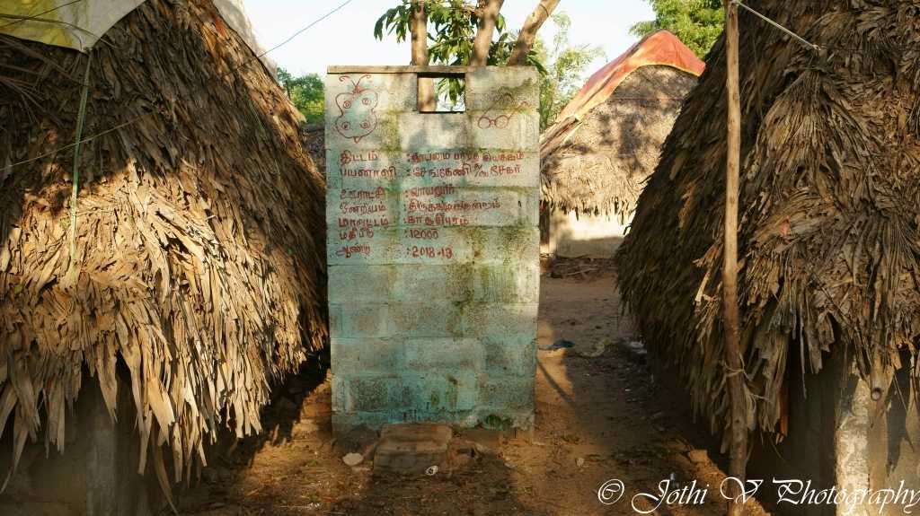 The concrete structure between the thatched huts is a toilet built under Swatch Bharat Abiyaan.